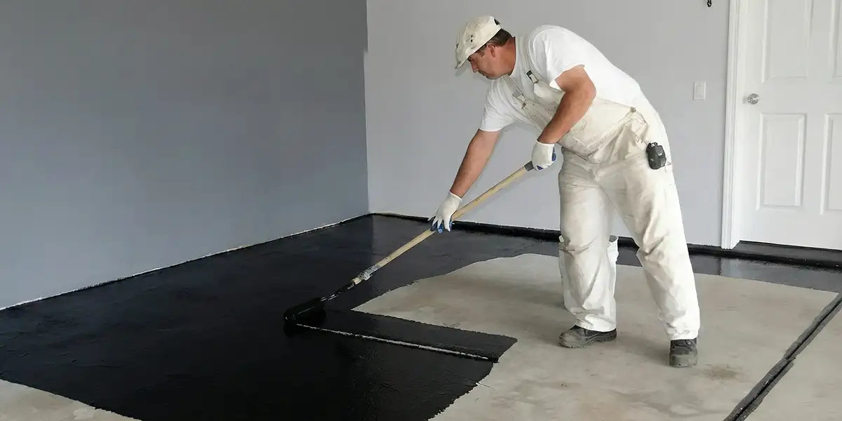 basement waterproofing professional applying waterproof coating to protect a basement floor in Denver, CO
